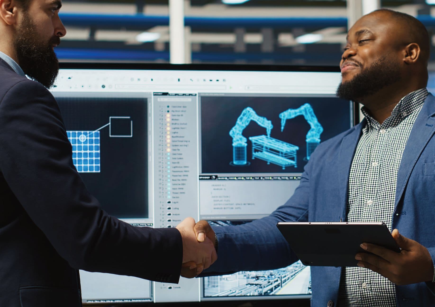 Two professionals shaking hands in front of an industrial control screen